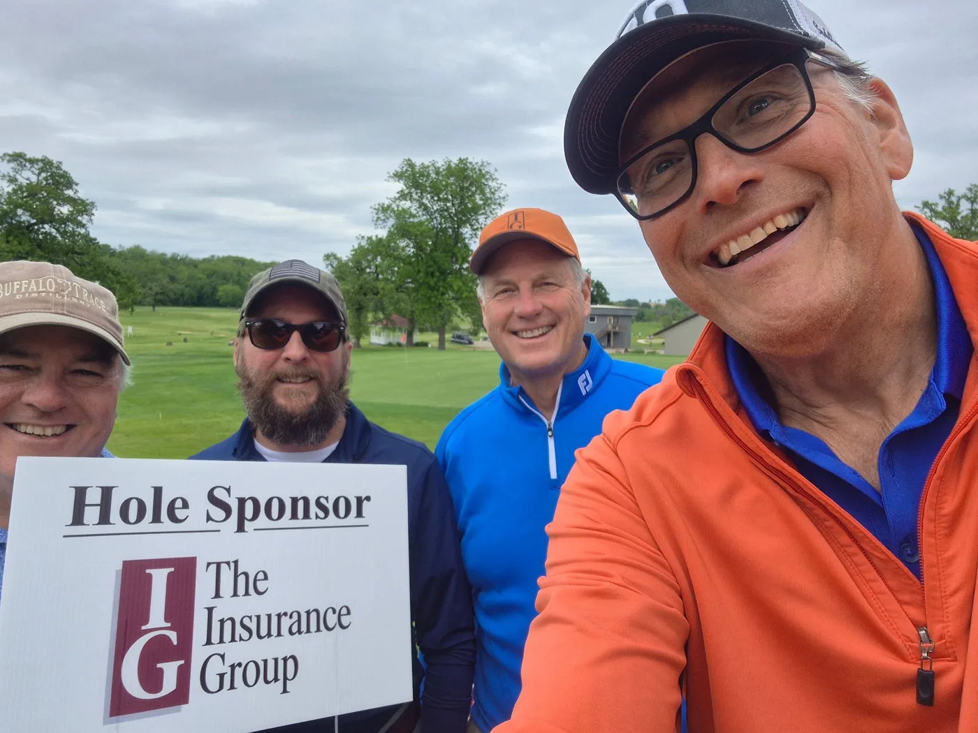 Four golfers smiling with a The Insurance Group hole sponsor sign